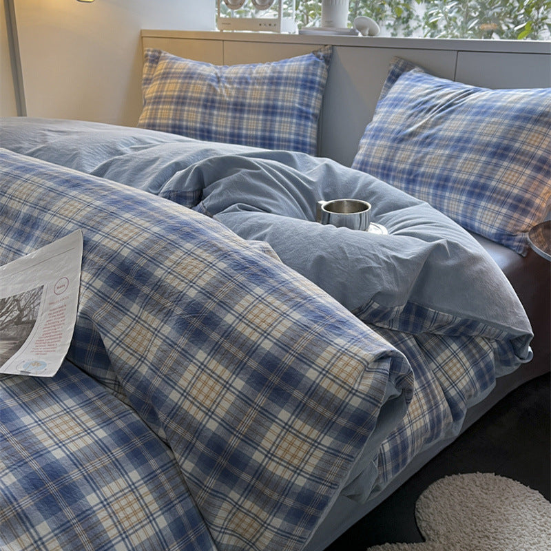 Bed with blue plaid bedding and pillows in a bedroom setting.