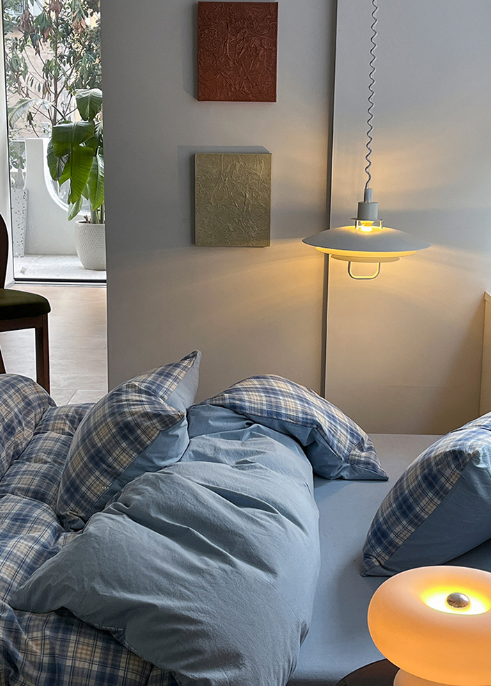Bedroom with plaid bedding and a hanging light fixture.