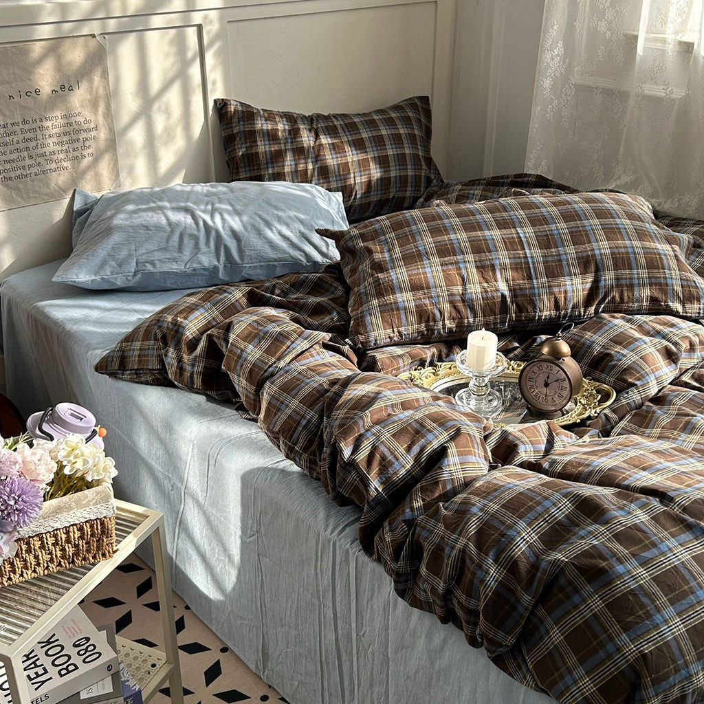 Bed with plaid bedding and pillows in a cozy bedroom setting.